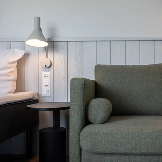 Hotel room seating area with green fabric sofa. Nordic design by Third.space.