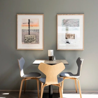 Small dining table in hotel breakfast area with custome-made wall art.